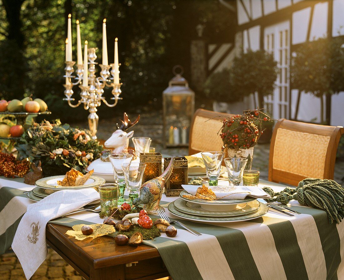Table with autumnal decorations, tableware & candlestick