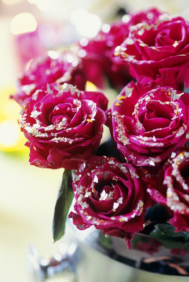 Rote Rosen mit Silberblättchen bedeckt in einem Sektkübel
