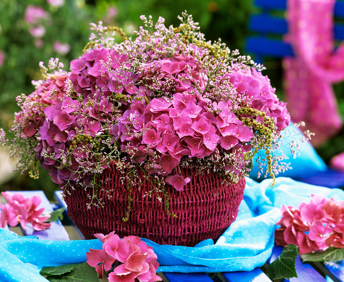 Hortensienblüten und Meerlavendel in rosafarbenem Korb