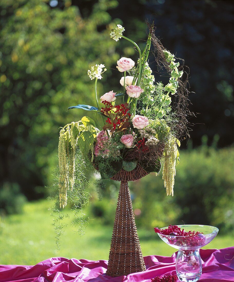 Wicker goblet with roses, celosia, sedum, ornamental asparagus