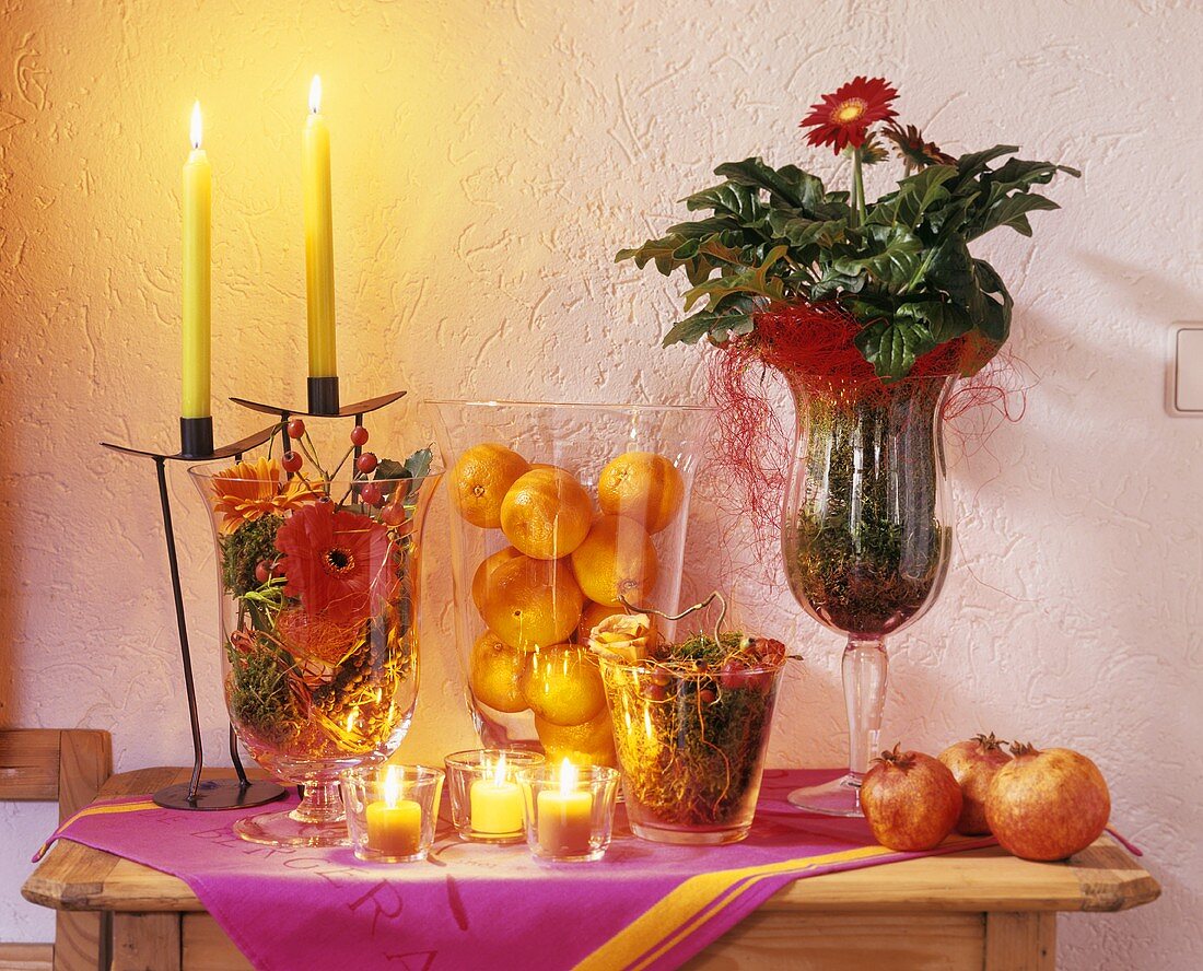Kerzen und Teelichter neben Obst in Gläsern & Topfgerbera