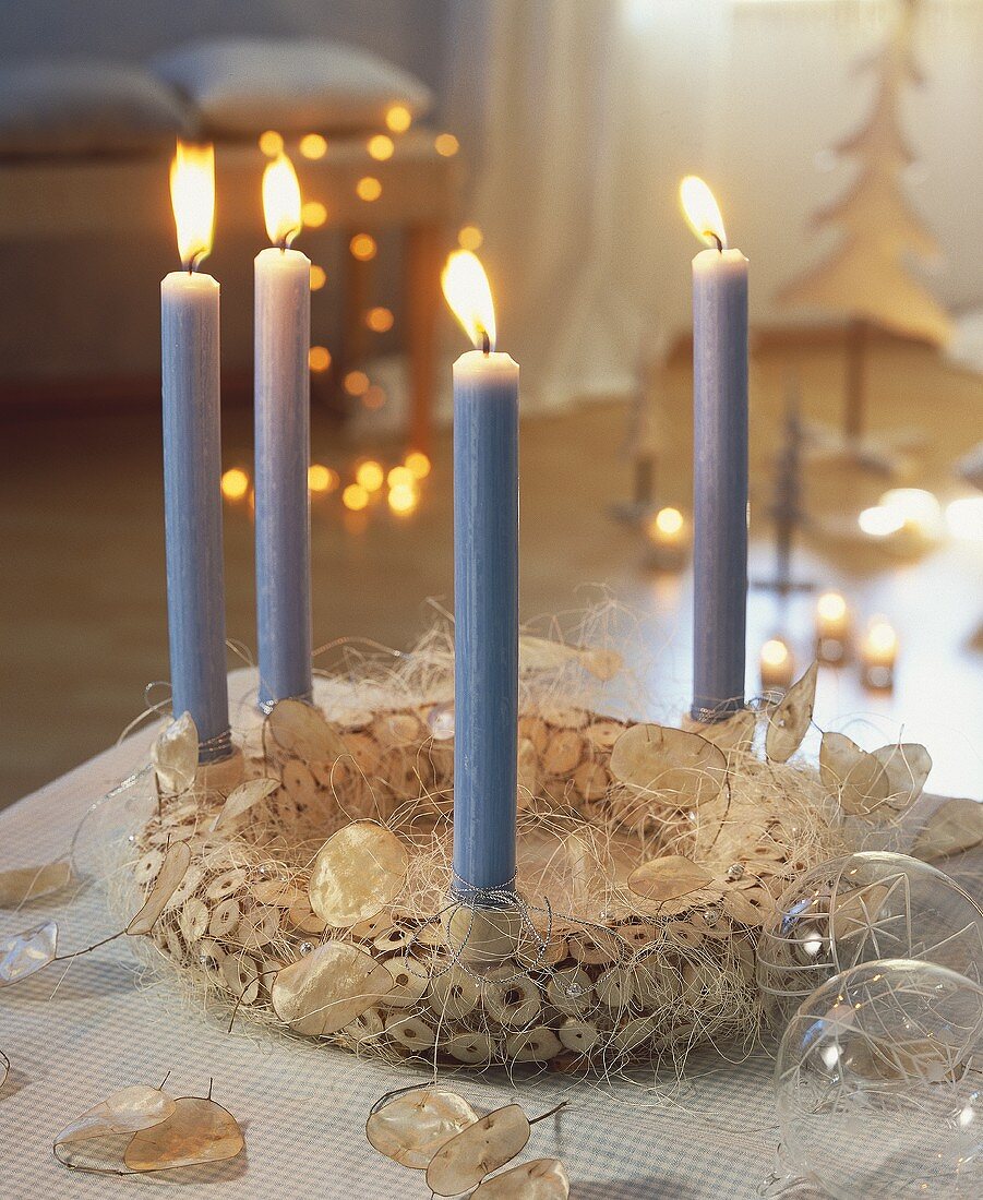 Weihnachtskranz aus Holzscheiben mit vier hellblauen Kerzen