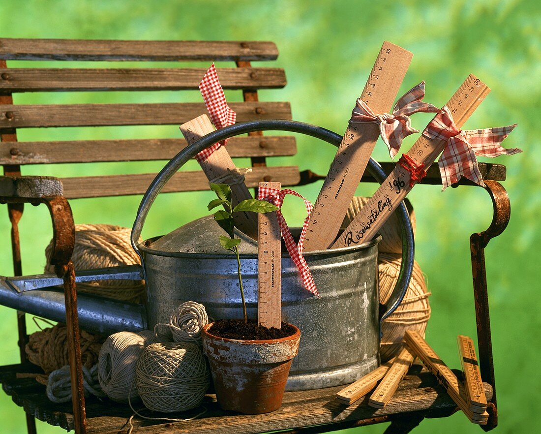 Old garden chair with watering can, wooden rulers, yardstick