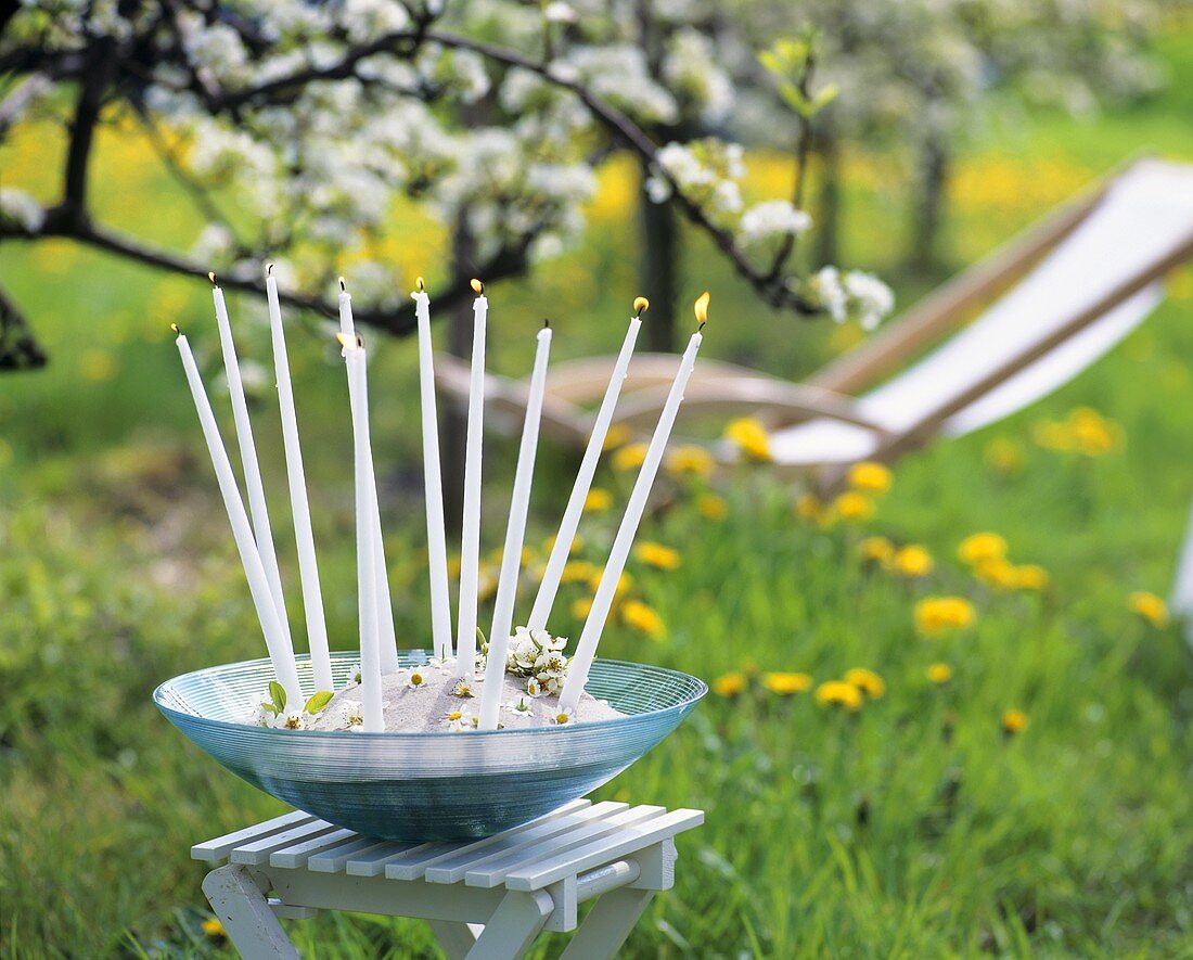 A bowl with ten candles and flowers standing in open air