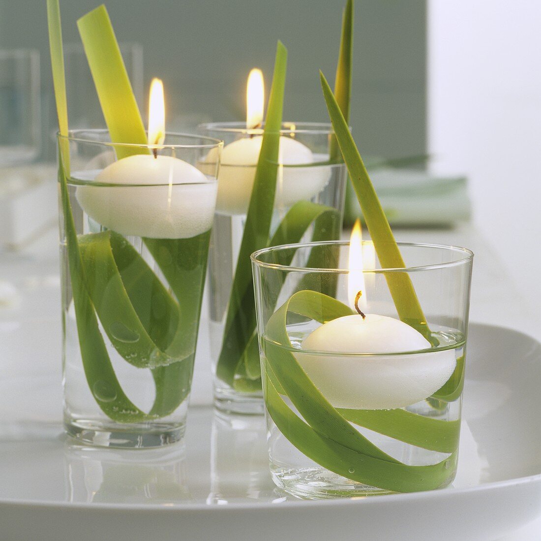 Frühlingsdeko mit drei schwimmenden Kerzen in Wassergläsern