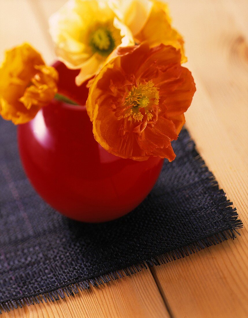 Flowers in a red vase on table cover on wooden table