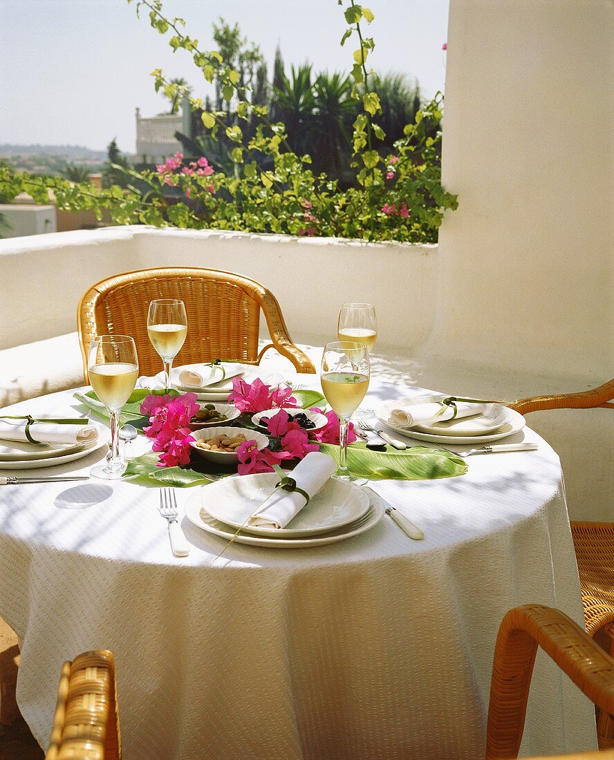 Gedeckter Tisch mit Oliven, Mandeln und Wein auf Terrasse