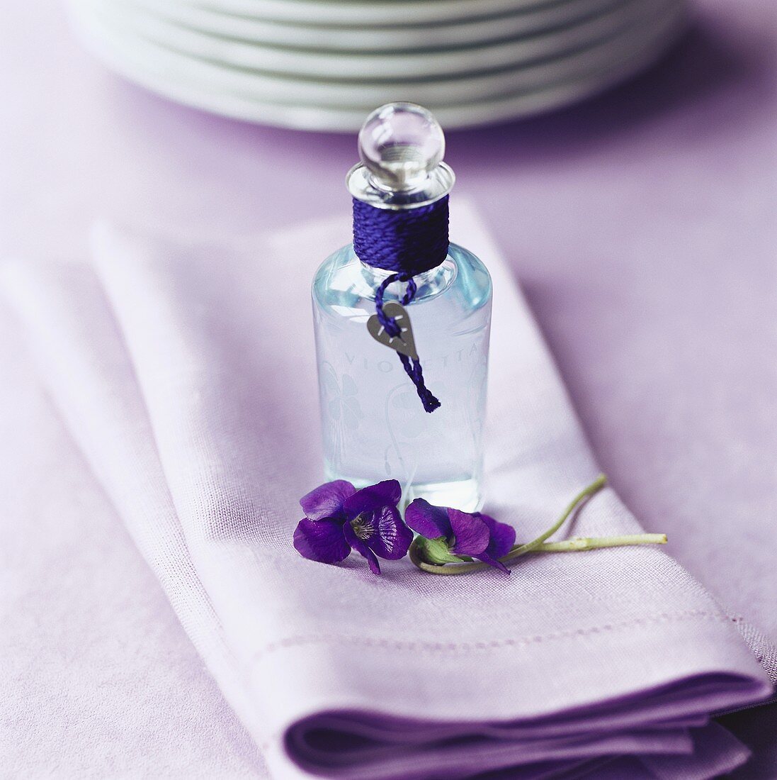 Flasche Veilchenwasser auf violetter Serviette
