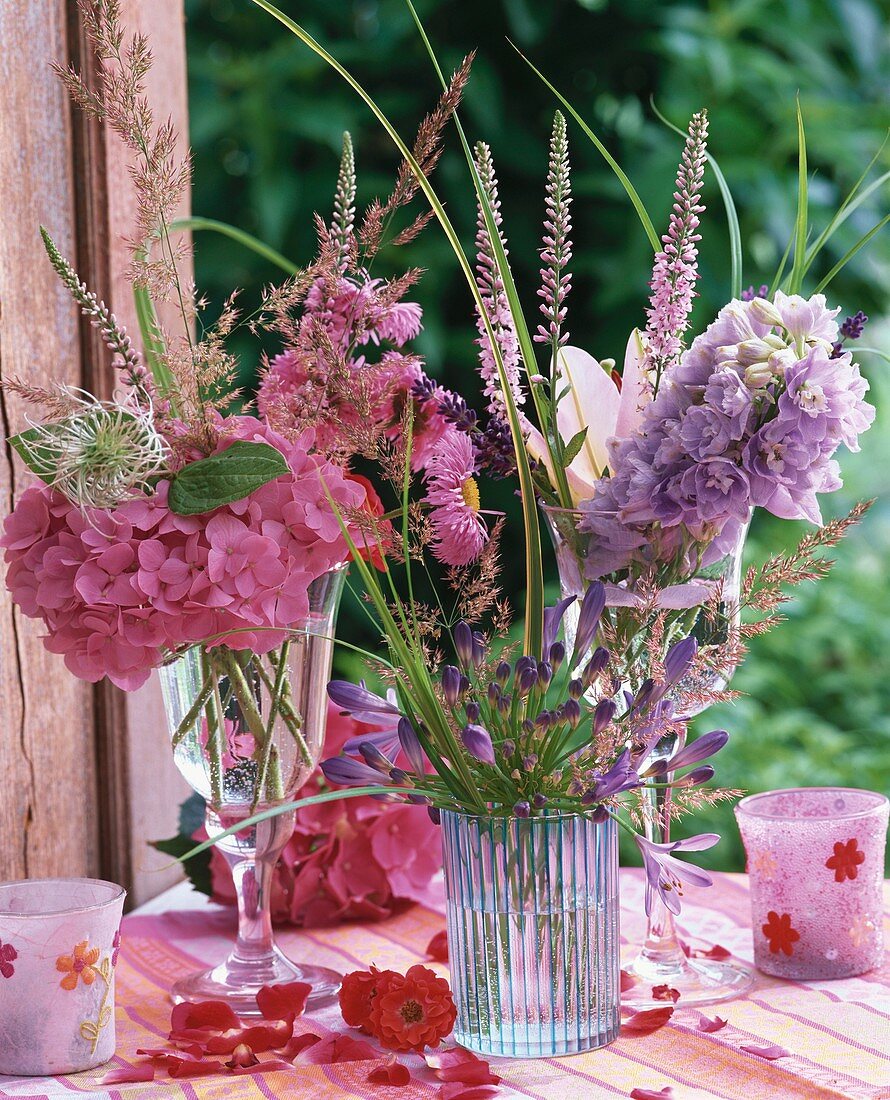 Summer flowers in glasses and wind lights on garden table