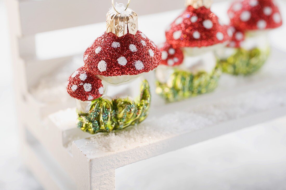 Christmas tree ornaments (fly agarics) on small bench in snow