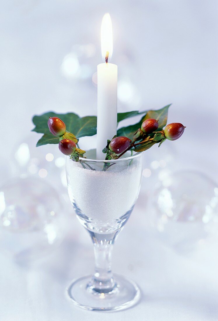 Festliche Tischdeko mit Kerze und Hagebutten im Weinglas