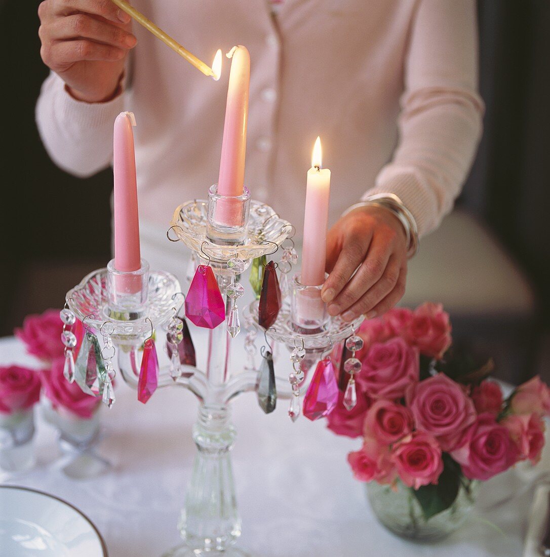Frau zündet Kerzen an auf festlich gedecktem Tisch
