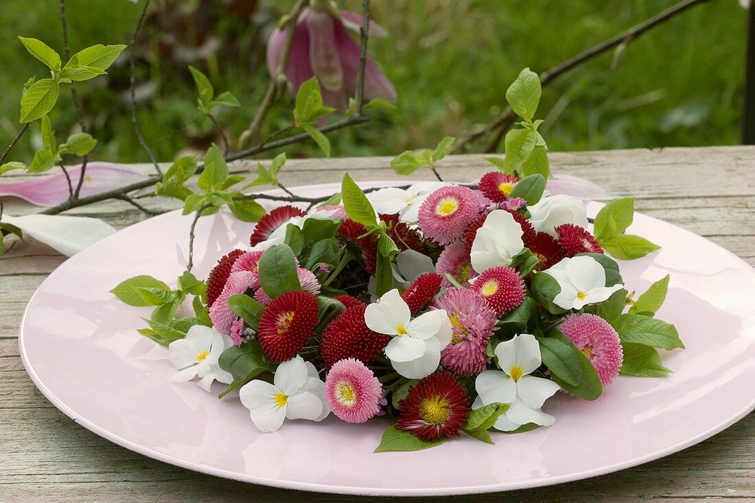 Wreath of Bellis and horned violets on table out of doors