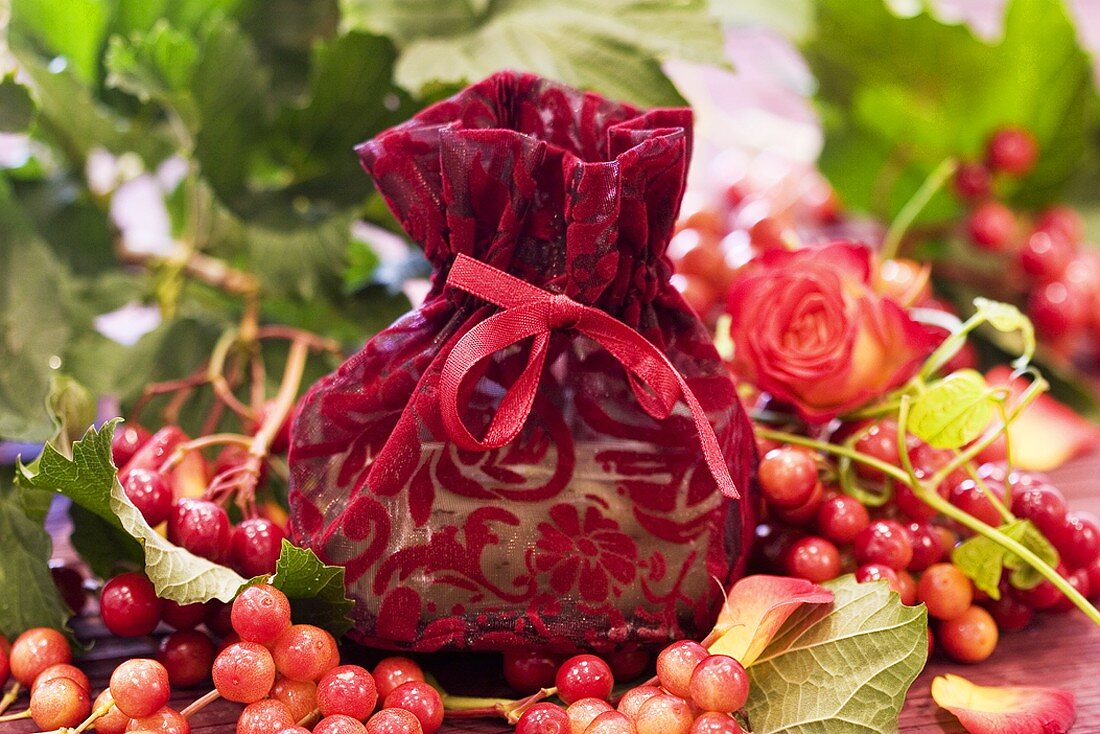 Small bag of soap surrounded by roses & guelder rose berries