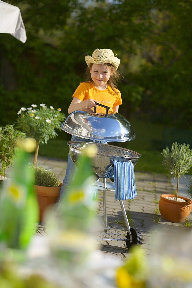 Child lifting the lid of a barbecue