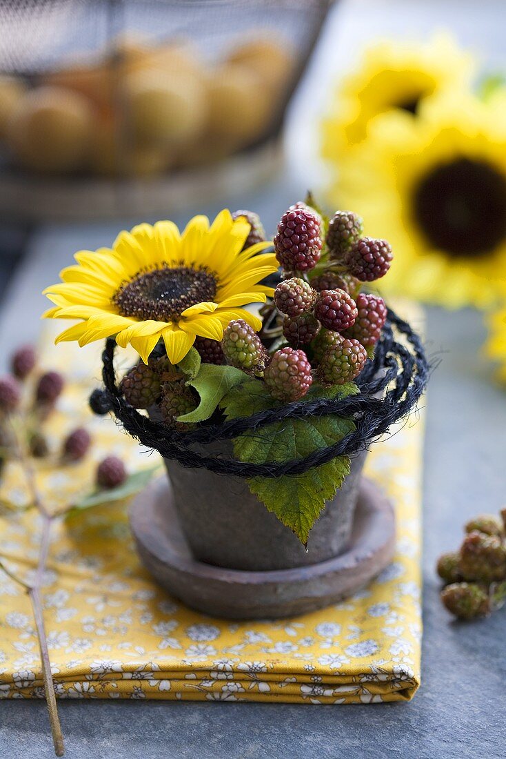 Gesteck aus Sonnenblume und Brombeerzweigen