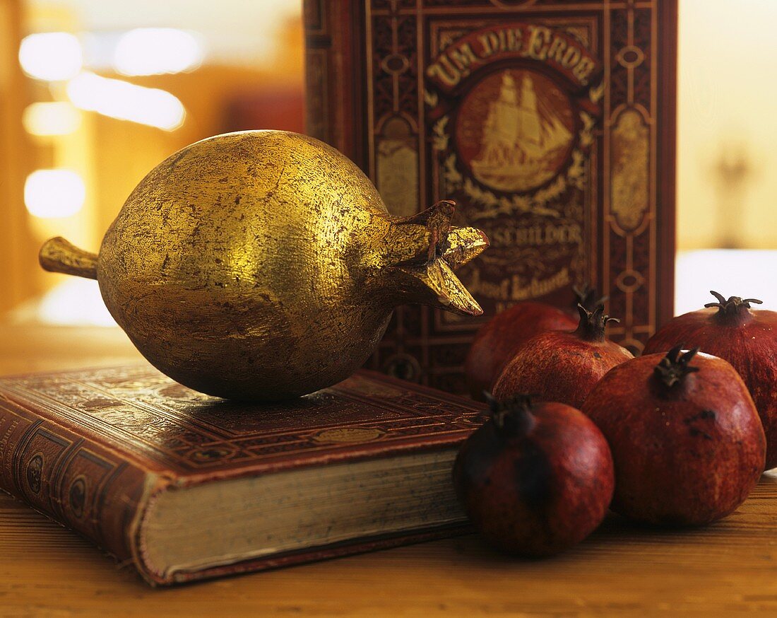 Pomegranate coated in gold leaf on old book