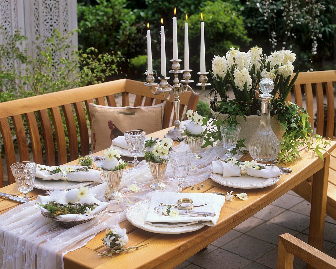 Weiß dekorierter Tisch mit Hyazinthen, Efeu und Hornveilchenblüten in ausgeblasenen Gänseeiern als Vasen