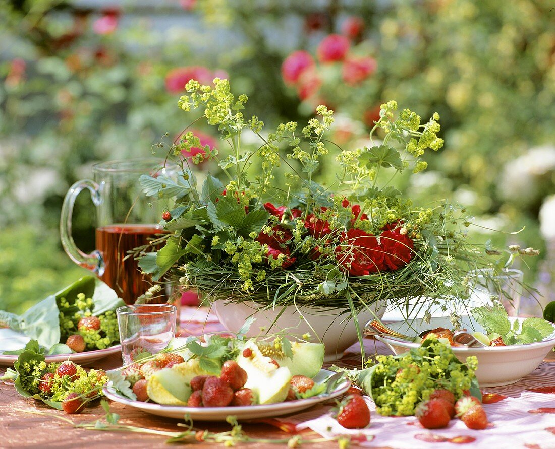 Sommertisch mit Erdbeeren und Honigmelone im Freien