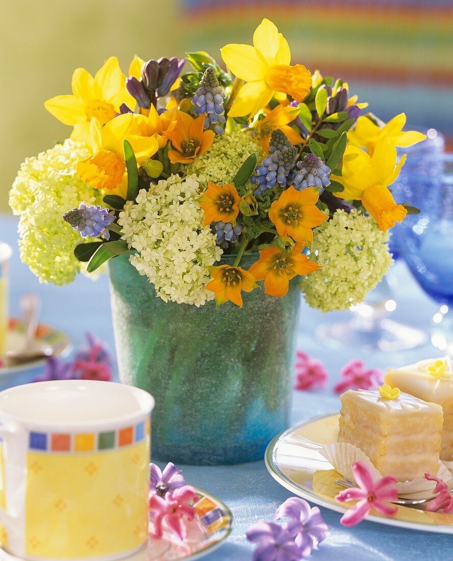 Spring flowers on table laid for coffee with petit fours