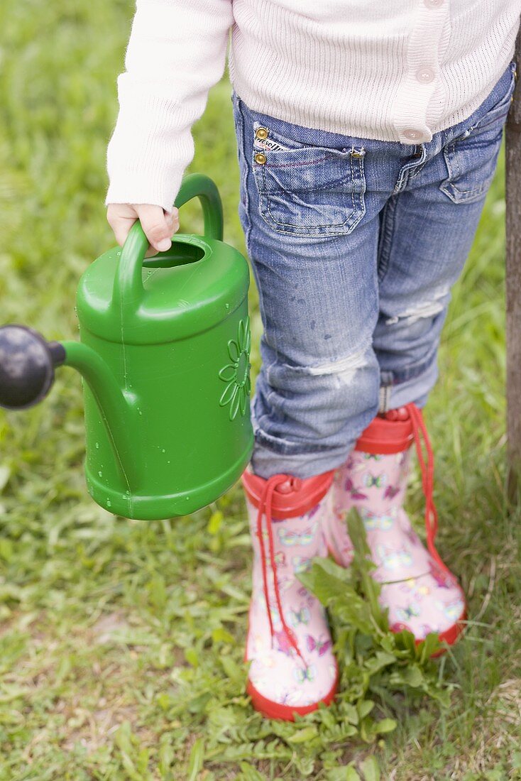 Child with watering can in garden