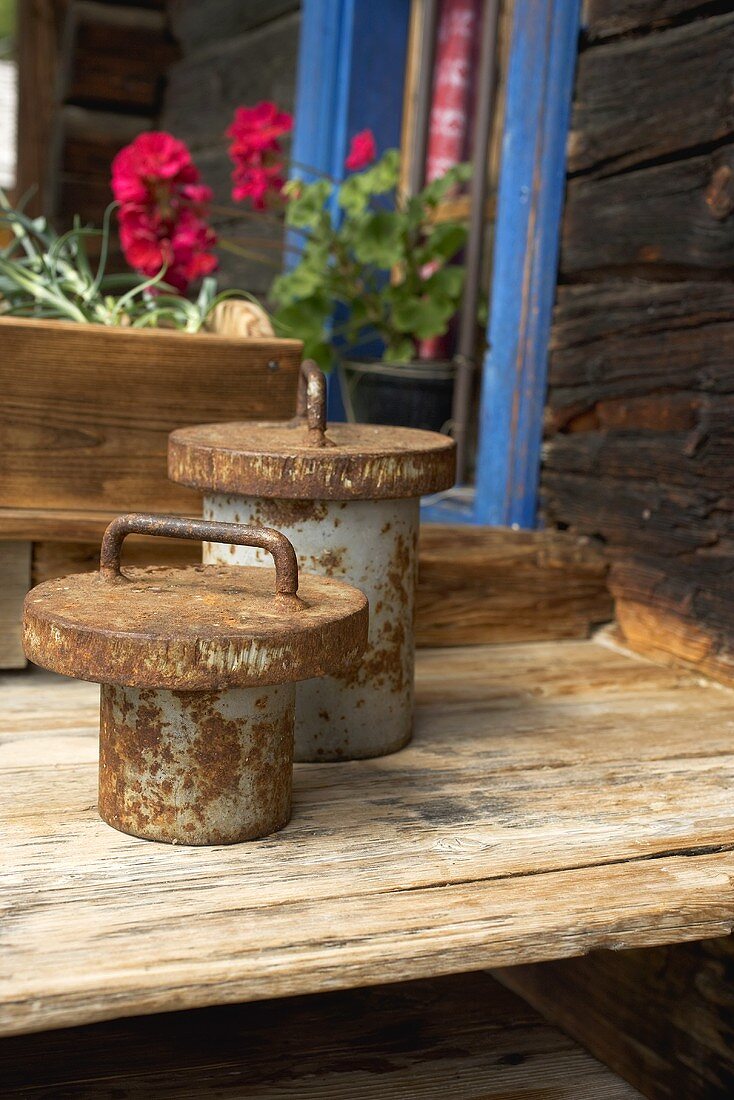 Rusty weights on wooden table outside a wooden house