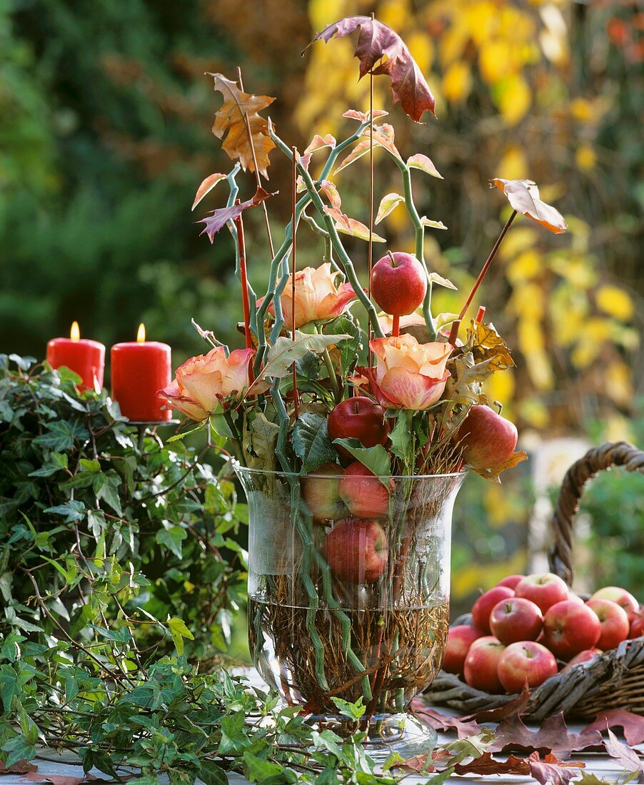 Glas mit Perilepta-Zweigen, Äpfeln, Blättern und Rosen