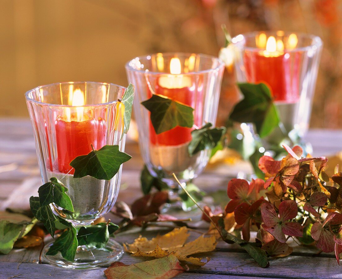 Weingläser mit Sand und roten Kerzen, Herbstlaub