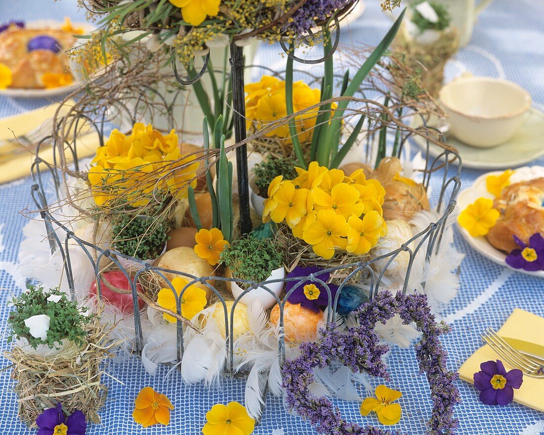 Drahtetagere mit Primelblüten, Ostereiern und Federn