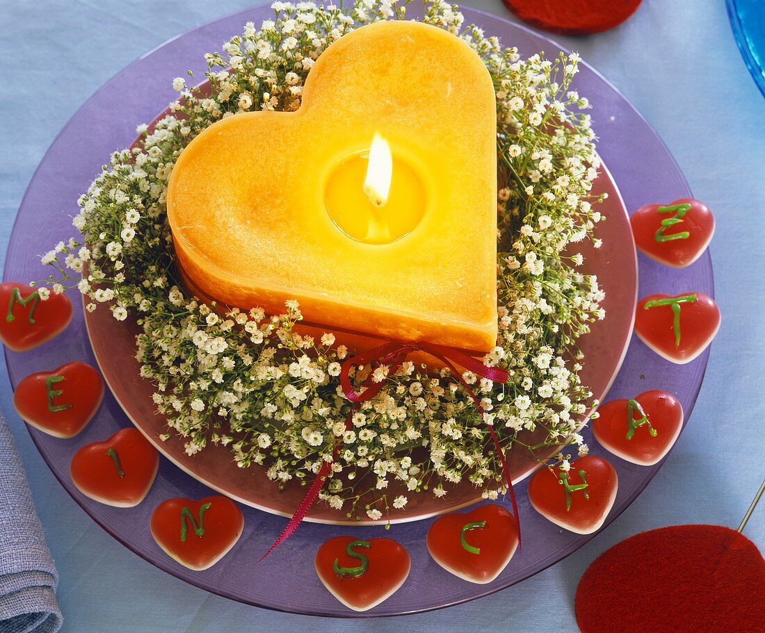 Gypsophila wreath around orange heart-shaped candle, with words