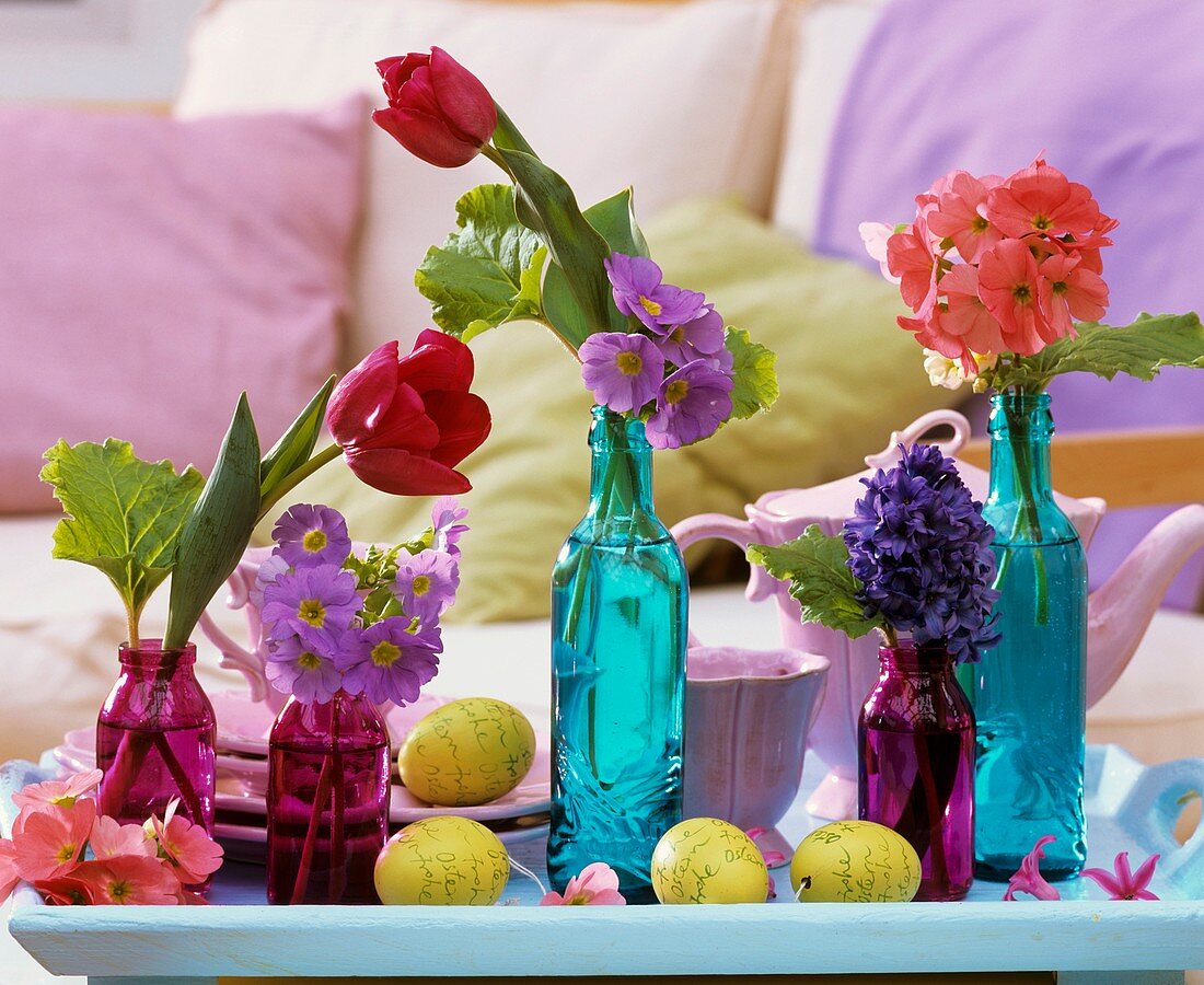 Bunte Glasflaschen mit Frühlingsblumen und Ostereier