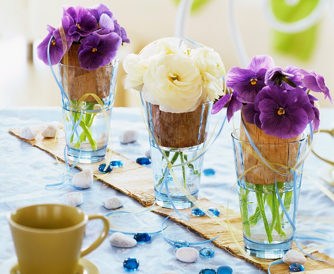 Pansies and Ranunculus in glasses with birch bark
