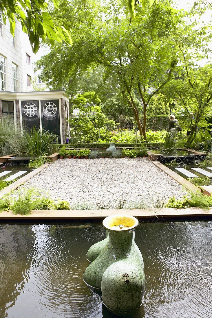 Gartenanlage mit Kiesfläche und Springbrunnen-Skulpturen in gefassten Wasserbecken