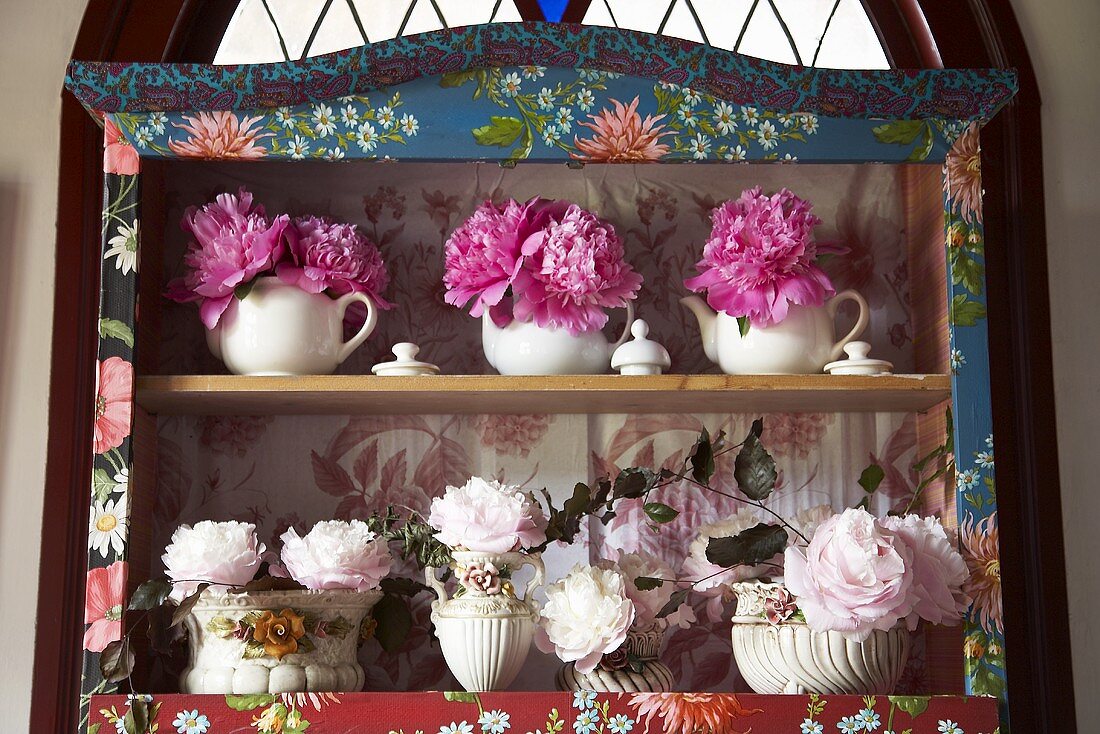 Peonies in various containers on shelves