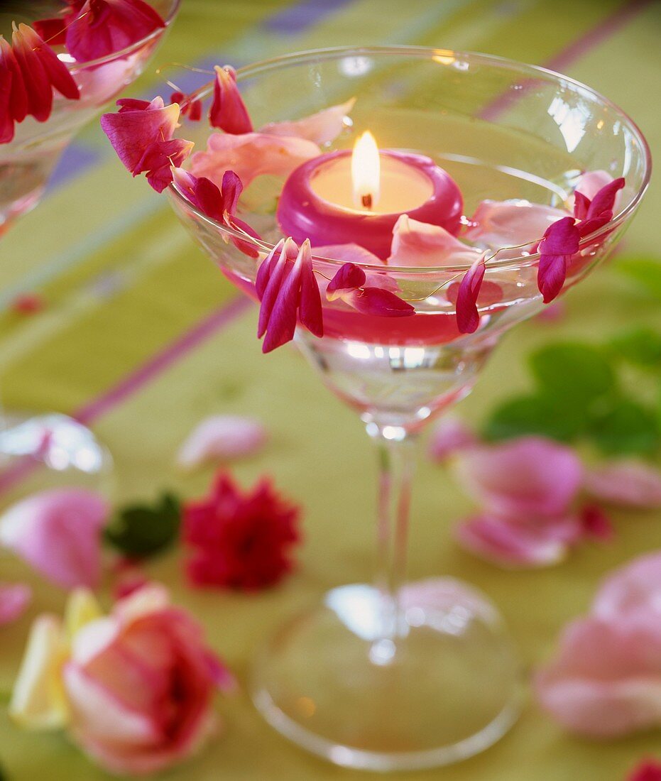 Glas mit Schwimmkerze und Rosenblütenblättern