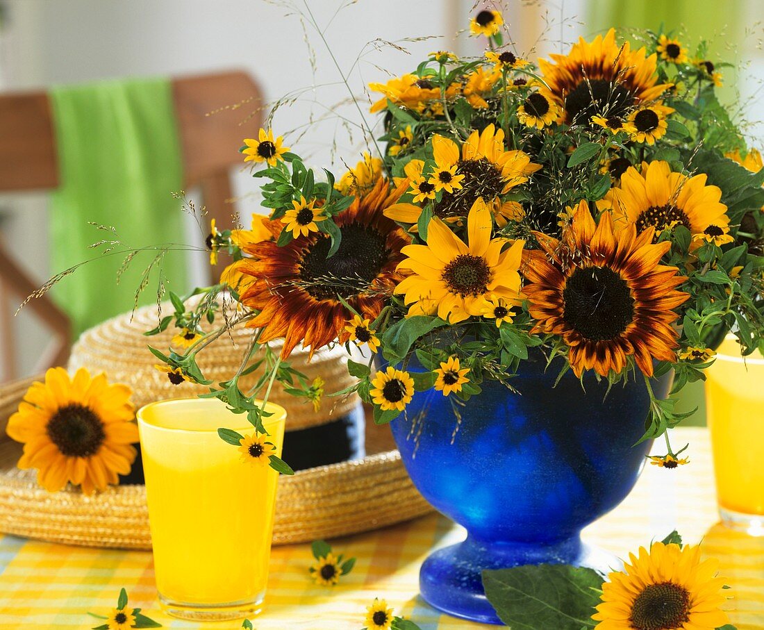 Arrangement of sunflowers and creeping zinnia in blue vase