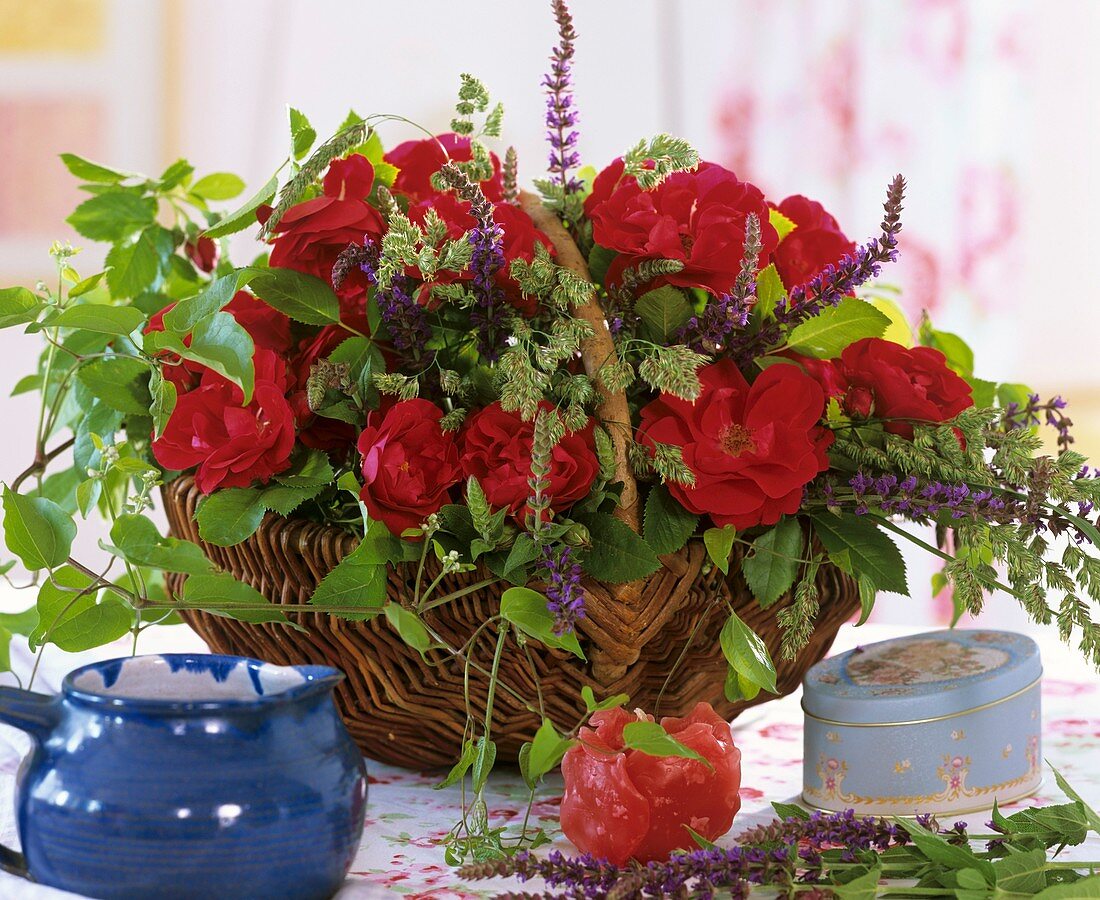 Basket of red roses, ornamental sage and Clematis shoots