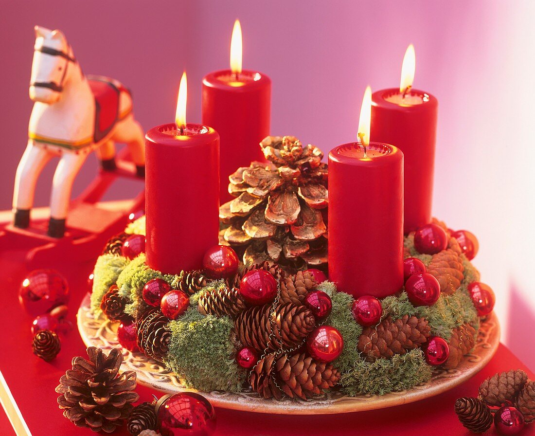Adventskranz aus Zapfen und Moos mit roten Kerzen