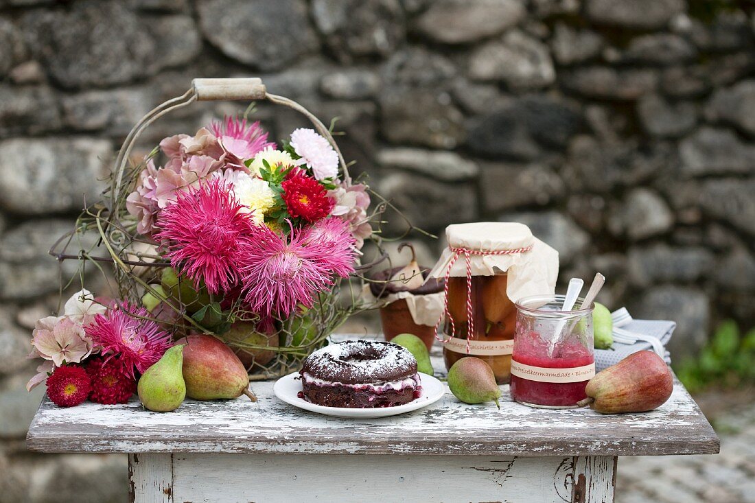 Chocolate cake with cream and jam filling, flowers, bottled pears and jam