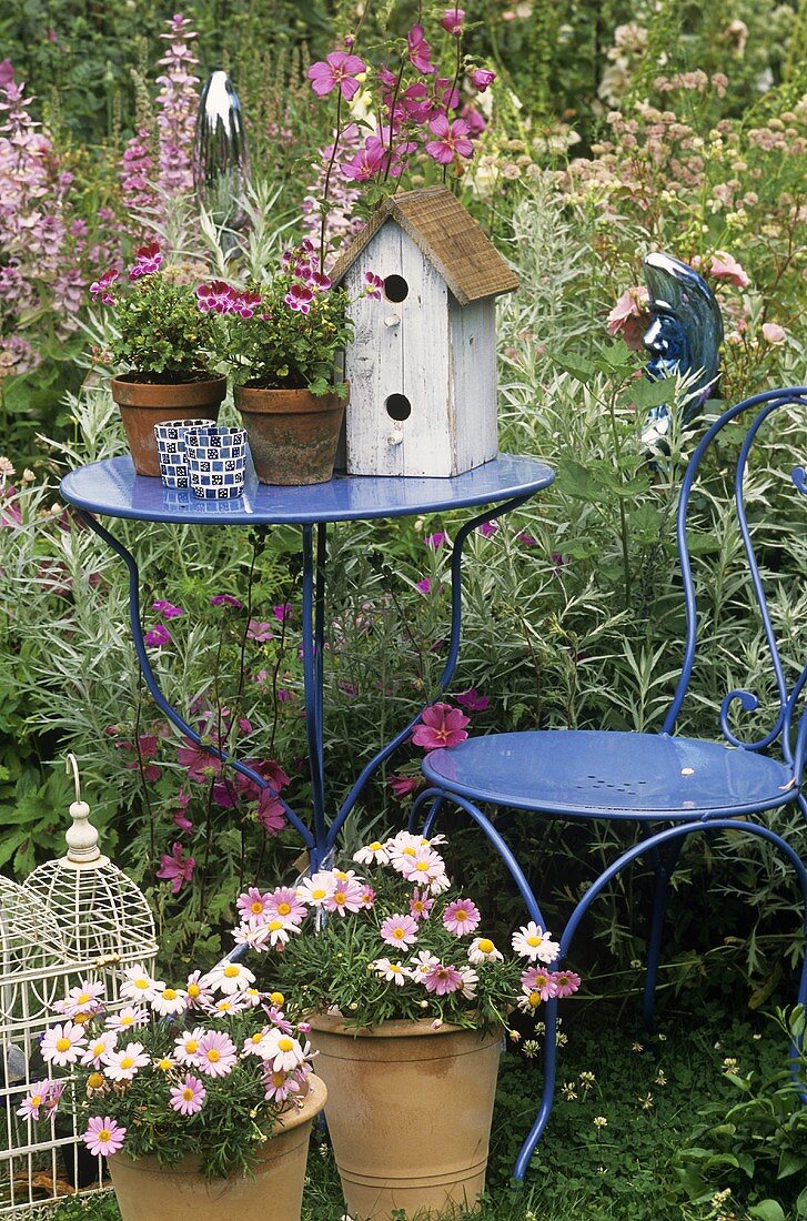 Gartentisch mit Blumen und Vogelhäuschen