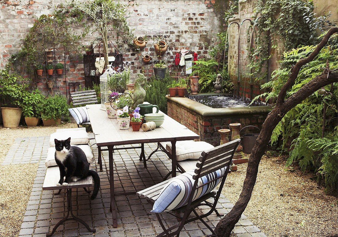 Romantischer Innenhof mit Pflanzen, Brunnen und Tisch