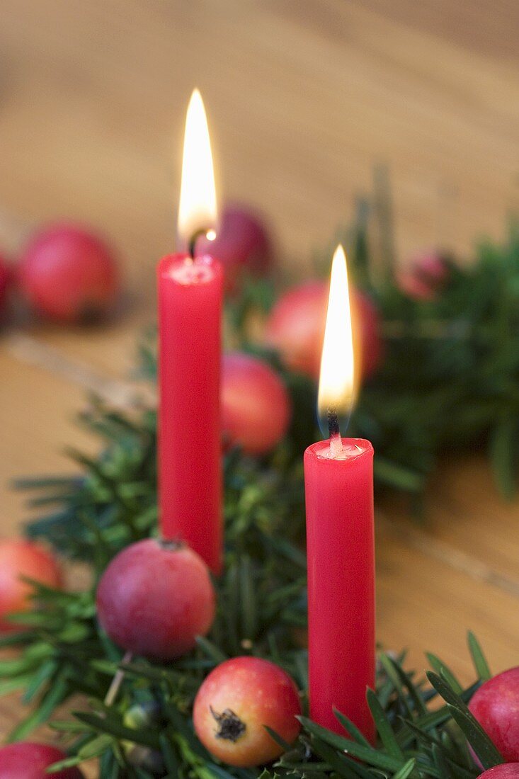 Weihnachtskranz aus Eibe mit Zieräpfeln und zwei roten Kerzen