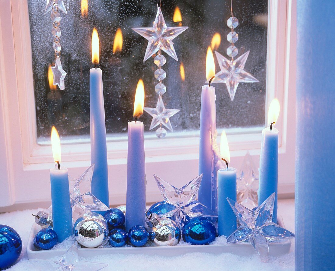 Blue candles, baubles and stars on tray by window