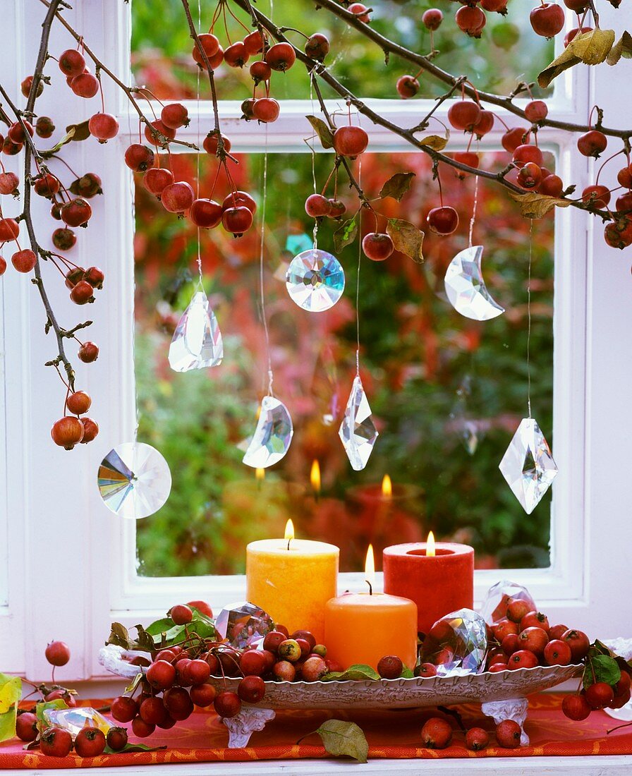 Zieräpfel, Glashänger und Kerzen am Fenster