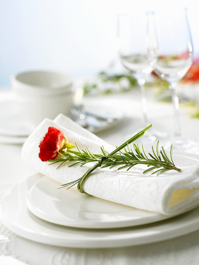White place-setting decorated with herbs and flower