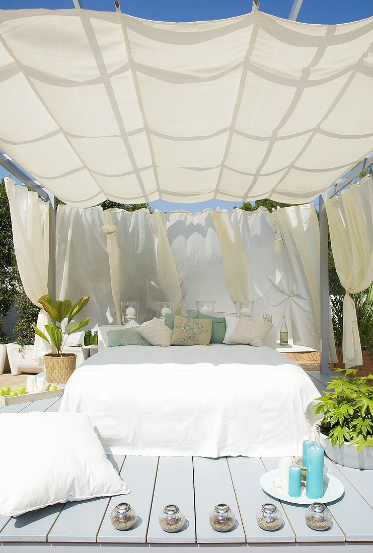 Lauschige Holzterrasse im Garten mit Sonnensegel über französischem Bett