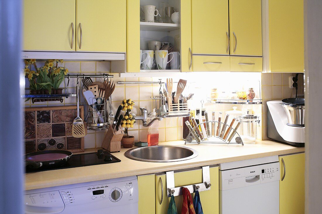 Moderne Küche mit gelben Einbauschränken, Waschmaschine und Spülmaschine