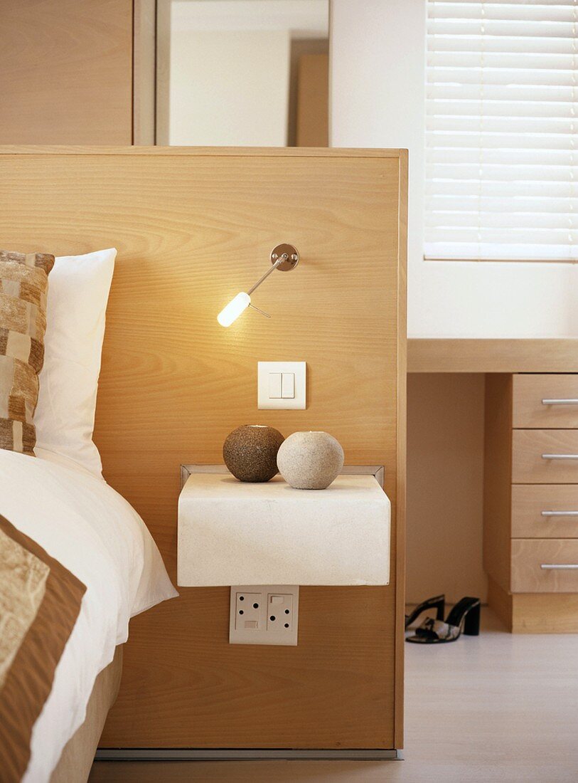 Headboard made of half-height partition with integrated reading lamp and bedside table