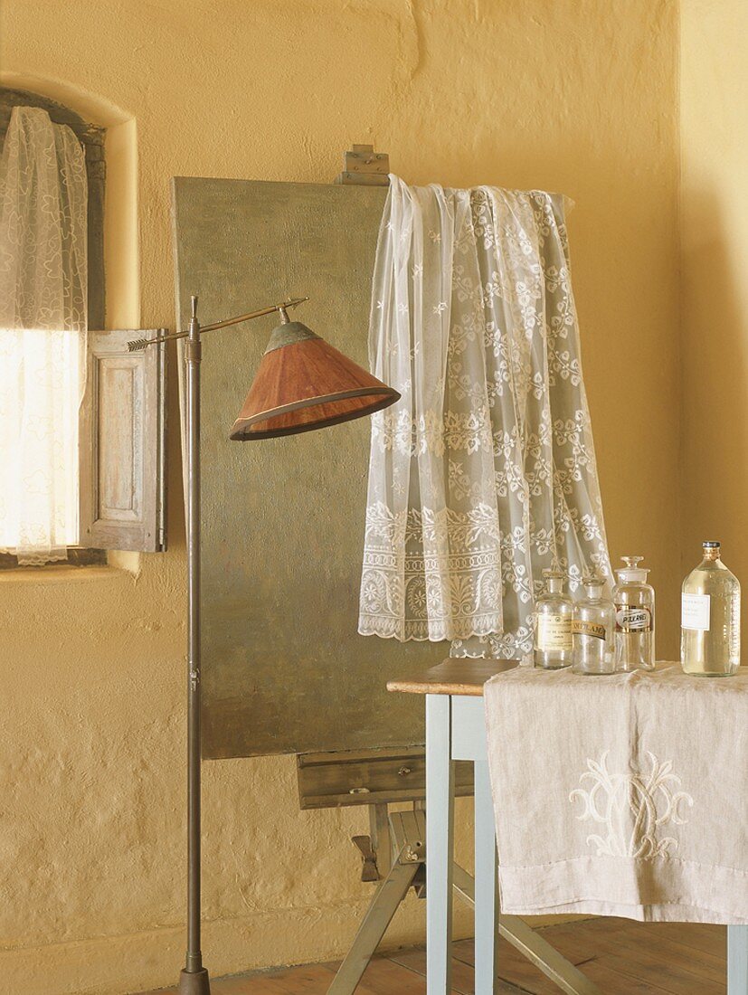 Badezimmer im romantischen Vintage-Look mit Spitzenvorhang über alter Staffelei und Apothekerflaschen