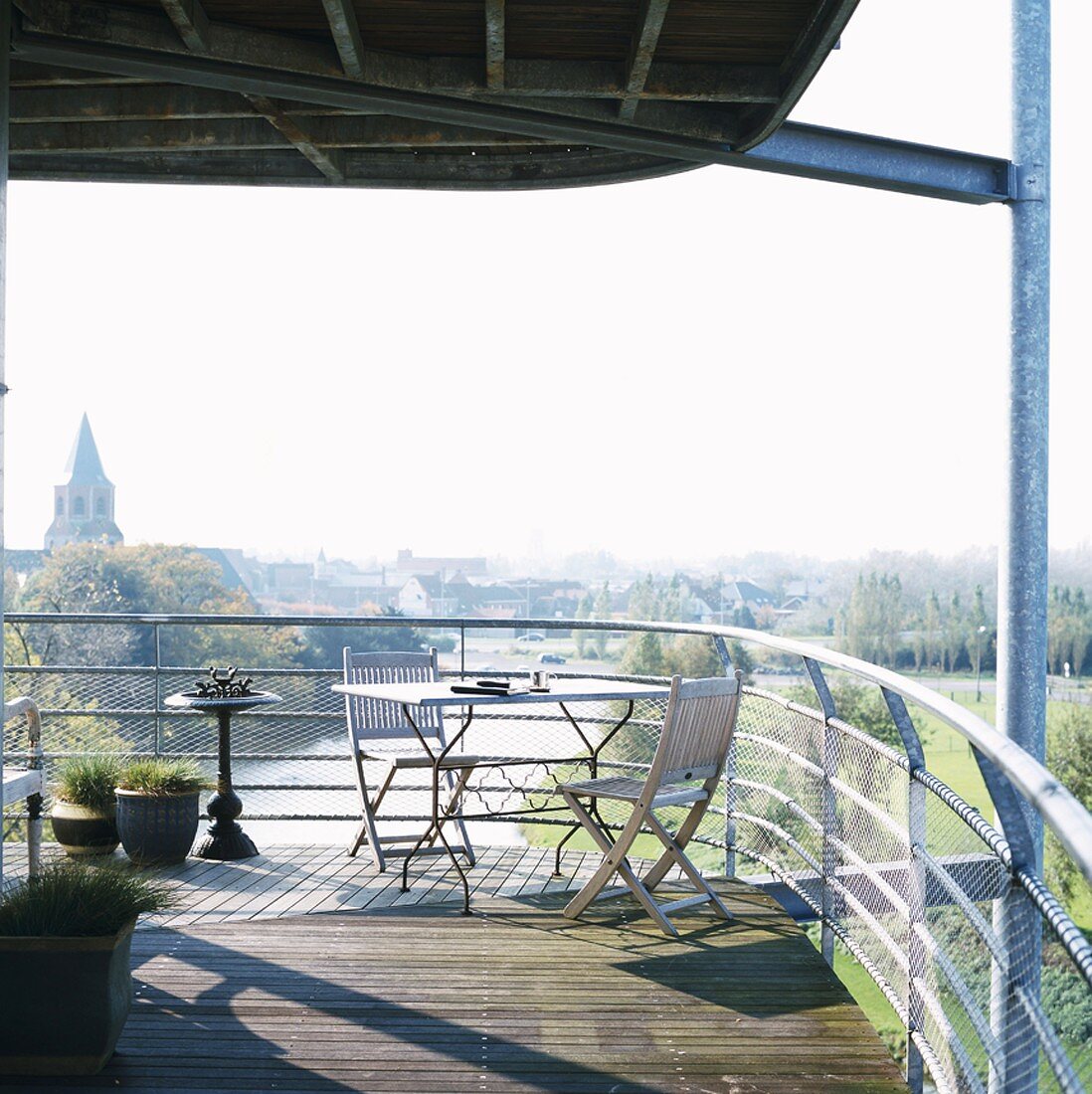 Modern, furnished terrace made from galvanised joists with wooden floor and view of river and cityscape